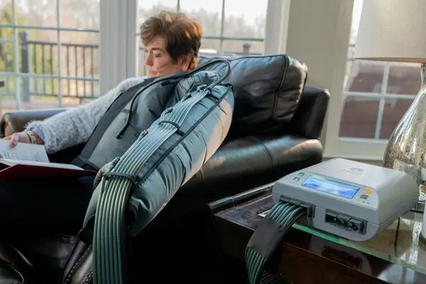 Woman using medical device on sofa.