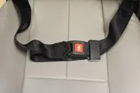 Black car seatbelt fastened on beige seat.