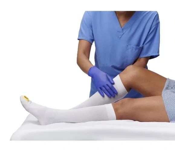 Medical professional wearing gloves examining a patient's leg.