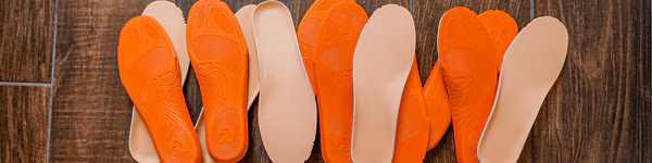 A close-up of various shoe insoles in orange and beige colors.
